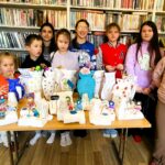 na zdjęciu widać dzieci stojące za stołem n którym poukładane są wykonane przez nie prace plastyczne