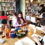 na zdjęciu widać salę biblioteczną i dzieci siedzące wokół stołu