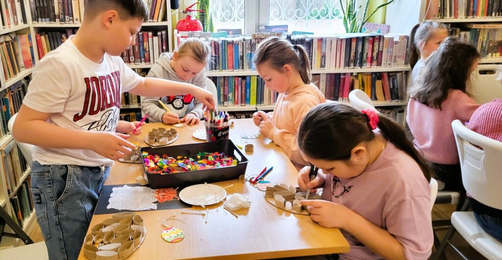 na zdjęciu widać dzieci przy stole tworzące prace plastyczne