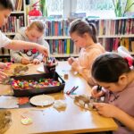 na zdjęciu widać dzieci przy stole tworzące prace plastyczne