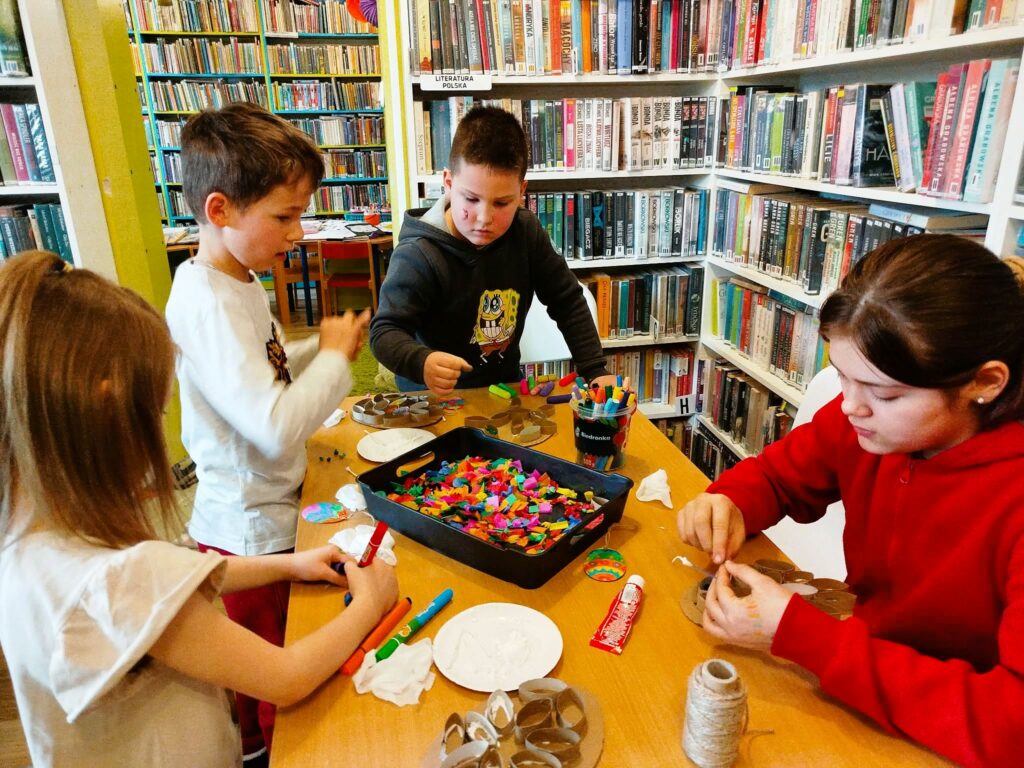 na zdjęciu widać dzieci przy stole tworzące prace plastyczne