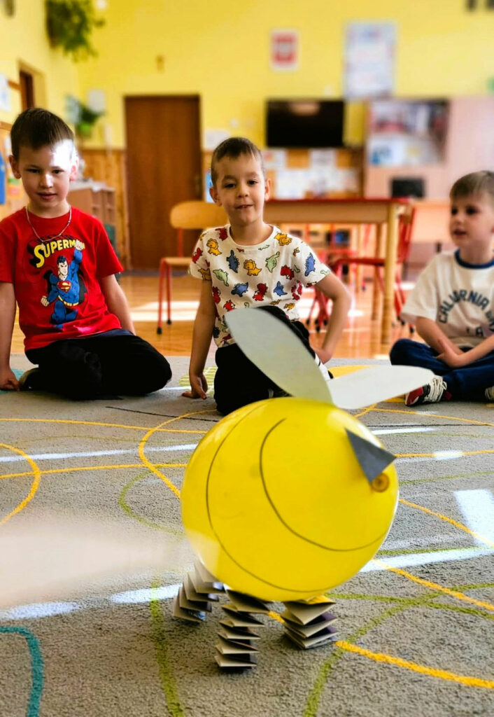 na zdjęciu widać balonową pszczołę a za nią siedzących chłopców