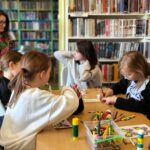 na zdjęciu widać kolorujące dzieci w sali bibliotecznej