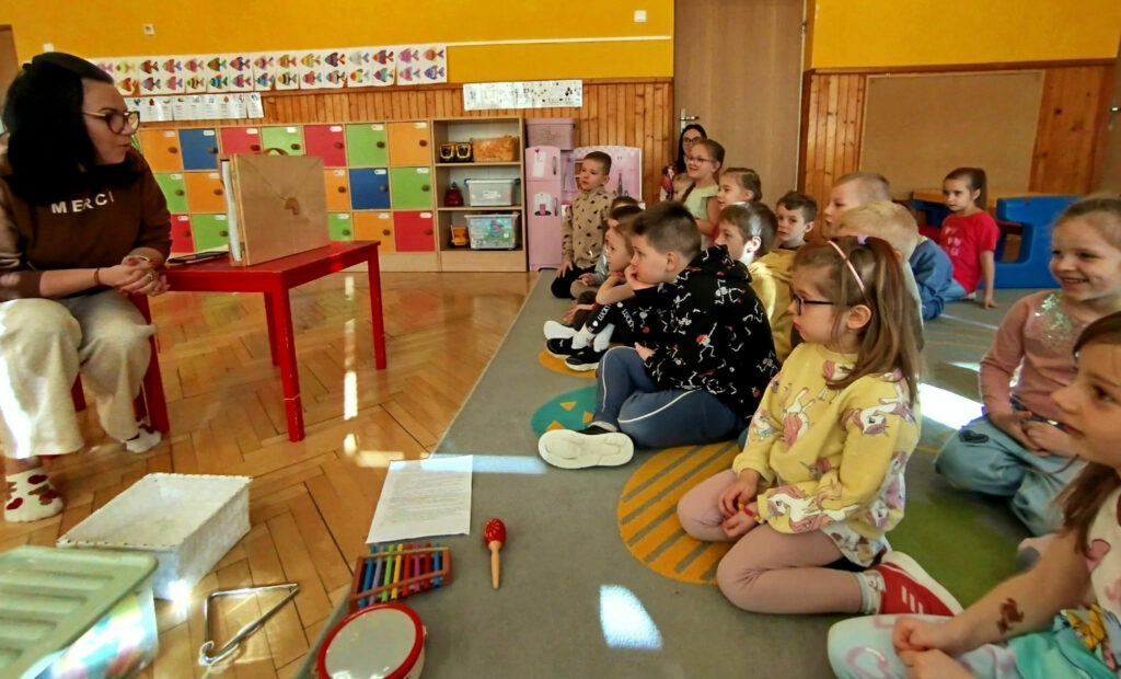 na zdjęciu widać dzieci w wieku przedszkolnym siedzących na podłodze