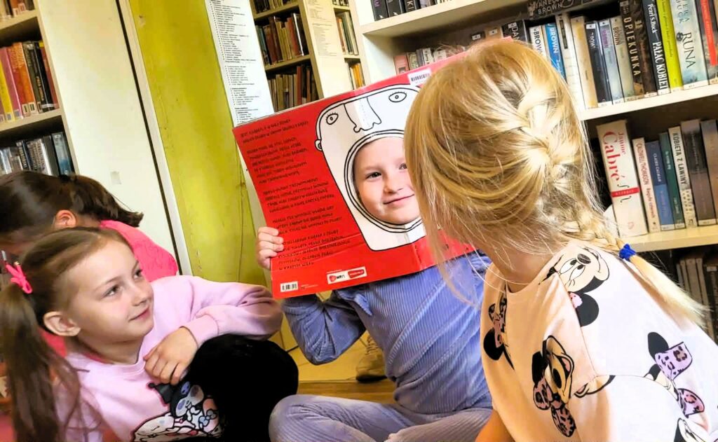 na zdjęciu widać dzieci trzymające książkę