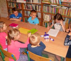 dzieci z uwagą słuchają opowieści czytanej przez jedną z uczestniczek zajęć