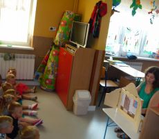 dzieci z uwagą słuchają opowieści o bordowej skarpetce prezentowanej w formie teatrzyku kamishibai