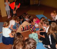 dzieci z zainteresowaniem przyglądają się teatrzykowi kamishibai