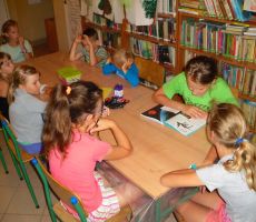 uczestnicy wakacyjnych zajęć w bibliotece słuchają dalszej części opowiadania czytanej przez kolejną z dziewczynek