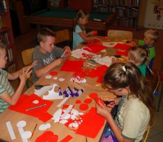 uczestnicy zajęć z czerwonego papieru wycinają płatki do swoich róż