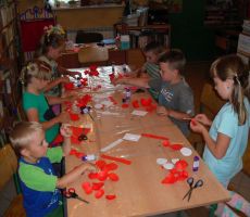 dzieci w skupieniu pracują nad swoimi papierowymi różami