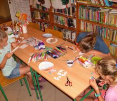 dzieci w skupieniu malują papierowe talerzyki, które będą tłem dla naszych kwitnących roślinek