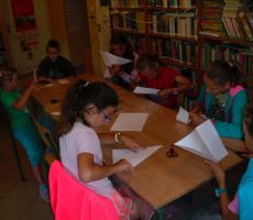 dzieci składają i wycinają białe kartki papieru według wcześniej pokazanej instrukcji