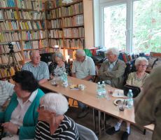 Licznie zgromadzeni w czytelni Biblioteki Publicznej goście siedzą przy stolikach i oczekują na projekcję przedwojennego filmu o Krynicy