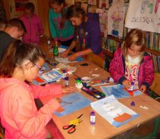 dzieci wyklejają okręty i żagle z kolorowych papierów