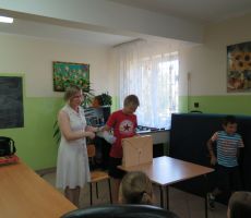 Zgromadzone na świetlicy dzieci siedzą na krzesłach i ochoczo zgłaszają się chcąc odpowiedzieć na pytania Pani Bibliotekarki