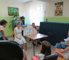 Pani Bibliotekarka razem z jednym z chłopców rozkłada na stoliku teatrzyk kamishibai