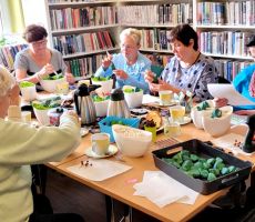 na zdjęciu widać panie siedzące wokół stołu w sali bibliotecznej