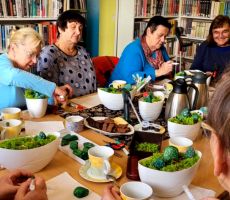 na zdjęciu widać panie siedzące wokół stołu w sali bibliotecznej