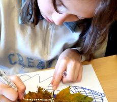 na zdjęciu widać dziewczynkę malującą liść